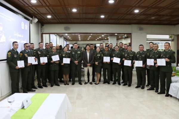 Imagen de 25 policías en traje de gala enseñando el diploma de certificación competencias laborales por parte del SENA 