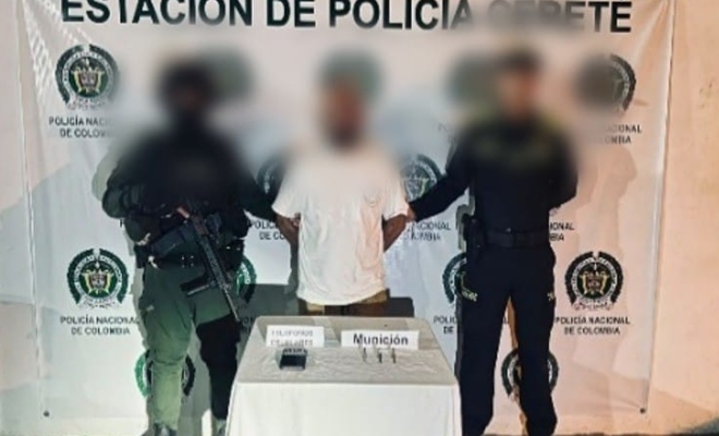 Dos funcionarios policiales con un ciudadano capturado frente a pendón institucional y frente a ellos mesa con material incautado 