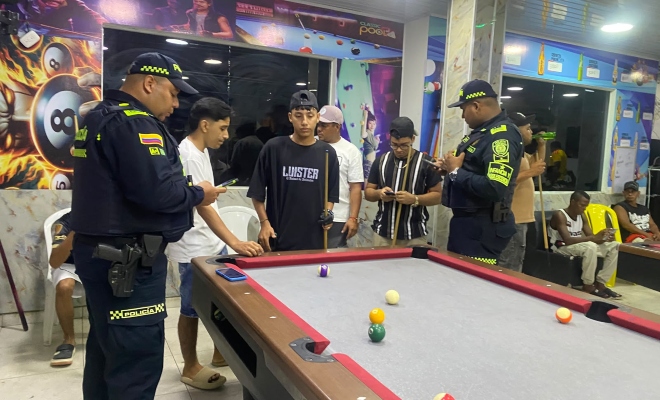 Dos funcionarios policiales realizando verificación de antecedentes a un grupo de ciudadanos en establecimiento publico