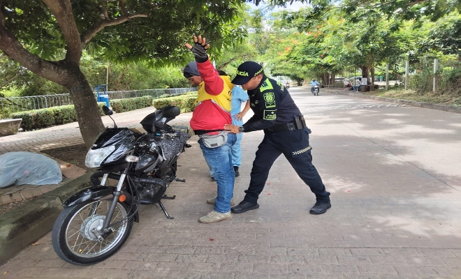 un uniformado realizando registro a persona en vía principal