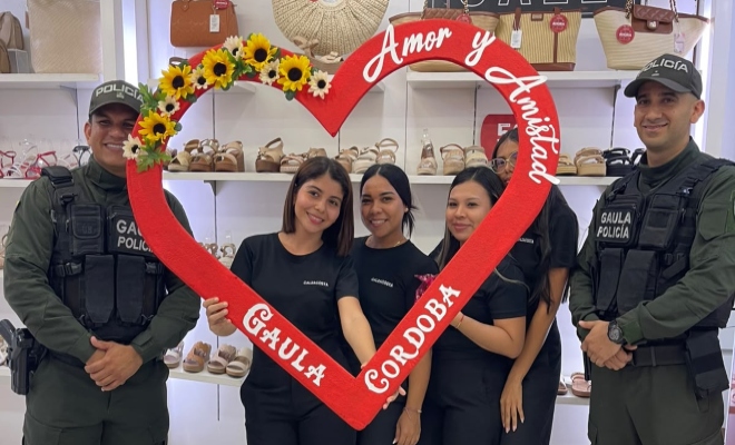 Cuatro ciudadanas junto a dos funcionarios policiales del Gaula sonriendo en actividad con un corazón del día de amor y amistad 