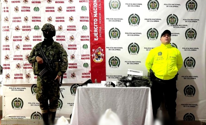 Un soldado y un policía custodian armas y uniformes incautados