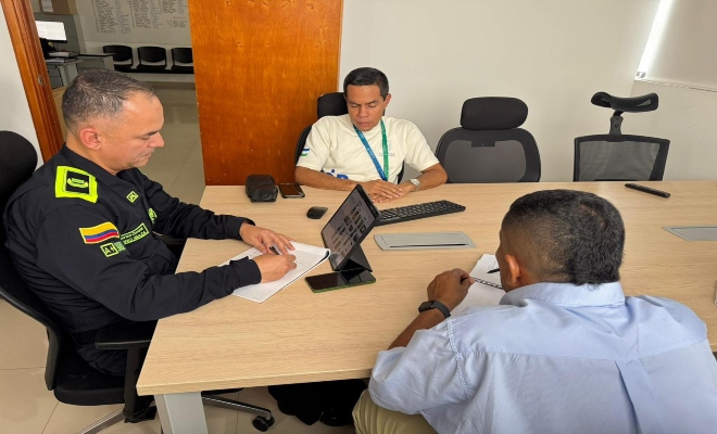 un uniformados con dos ciudadanos en reunión  sobre eventos que re realizaran en la ciudad de montería