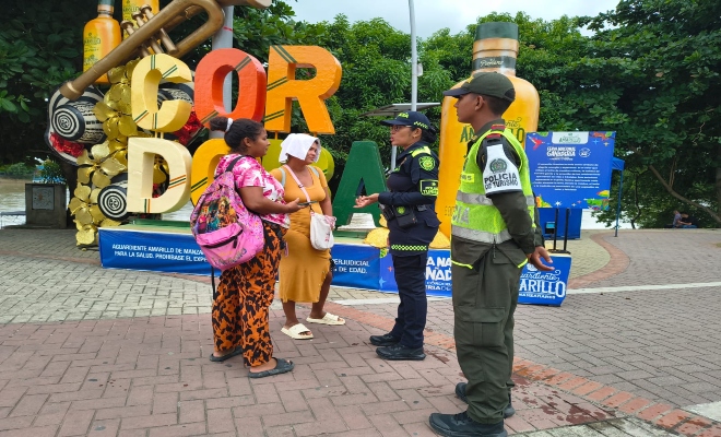 dos uniformados realizando campaña de prevención a dos ciudadana para garantizar la tranquilidad de propios y visitantes 