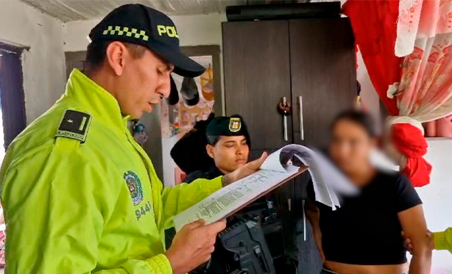 Funcionario de Policía Judicial realiza lectura de derechos de capturado a mujer capturada.