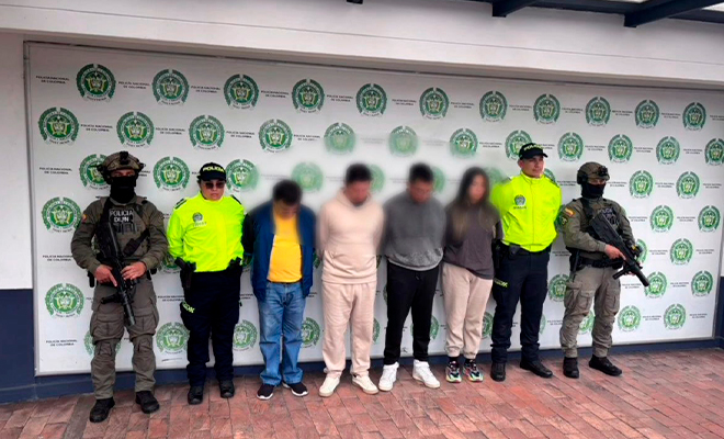 Cuatro capturados son custodiados por funcionarios de Policía, en un backing.