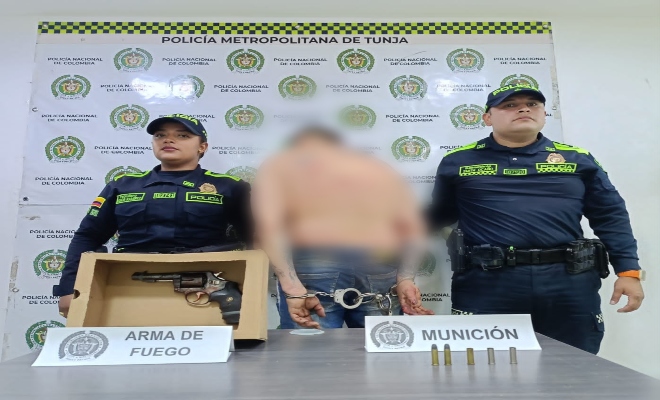 una persona capturada, a los lados dos uniformados y en la mesa se encuentra un revolver con 5 cartuchos para la misma 
