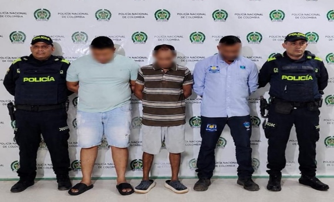 Dos policias custodian a tres sujetos capturados por hurto