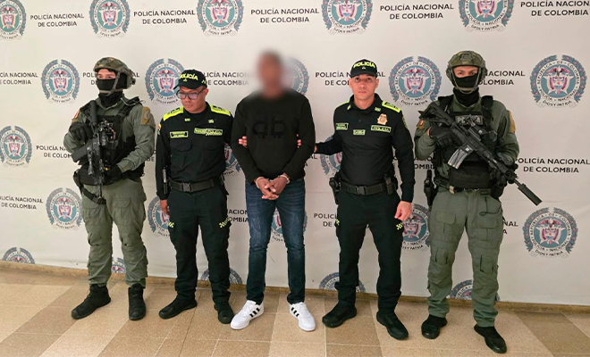 El capturado alias "Colombia" es custodiado por cuatro policías en el backing.