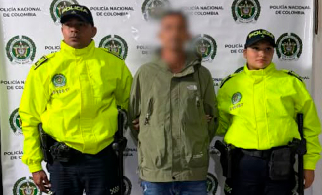 Alias 24 del EGC posa en el backing como capturado y custodiado por dos policías