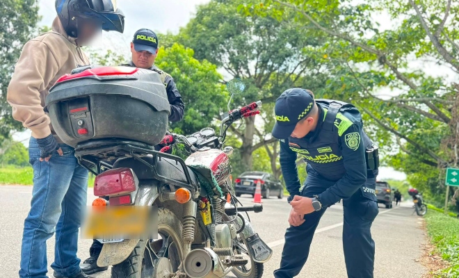 Funcionario policial realizando consulta de antecedentes a motocicleta junto a dos ciudadanos en actividades de prevención  