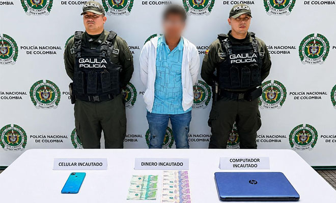 La imagen muestra a dos uniformados del GAULA de la Polic&iacute;a Nacional junto a una persona capturada, cuya identidad est&aacute; protegida. En la parte inferior se presentan los elementos incautados durante el procedimiento: un tel&eacute;fono celular, dinero en efectivo y un computador port&aacute;til