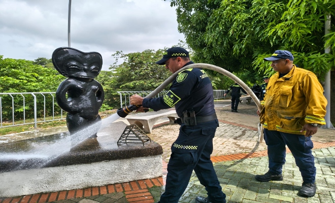 Un policía y un ciudadano realizando limpieza en el monumento 