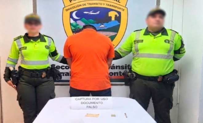 Dos funcionarios policiales de transito con un ciudadano capturado frente a una mesa con material incautado