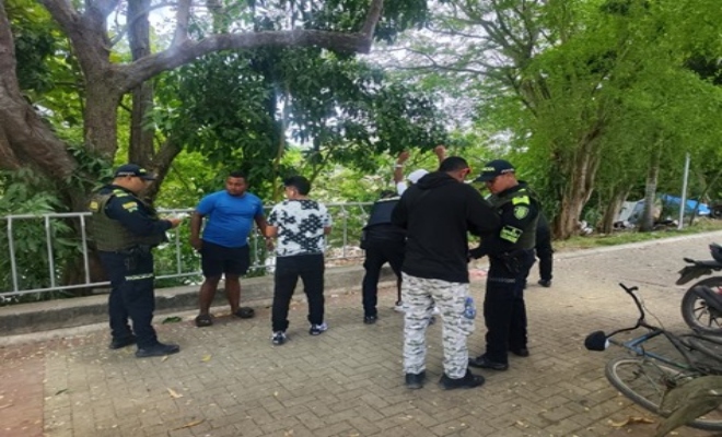 dos policias registrando a dos ciudadanos y un policia verificando documentos a dos ciudadanos 