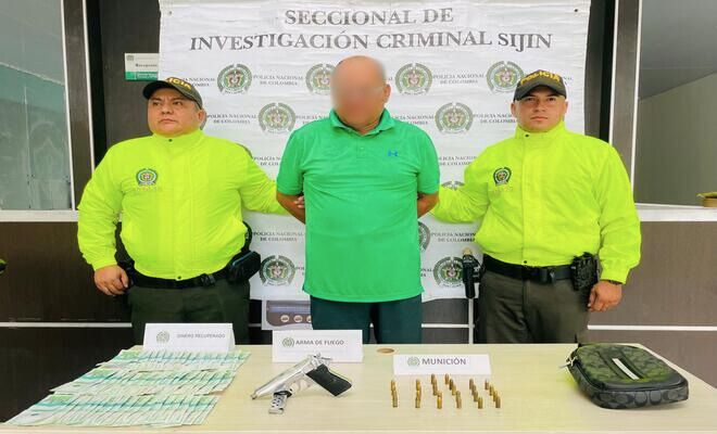 Dos Uniformados de la Polic&iacute;a Nacional de Colombia junto a un capturado. Se observan elementos incautados como dinero en efectivo, un arma de fuego, munici&oacute;n y una motocicleta utilizados en el hecho delictivo.