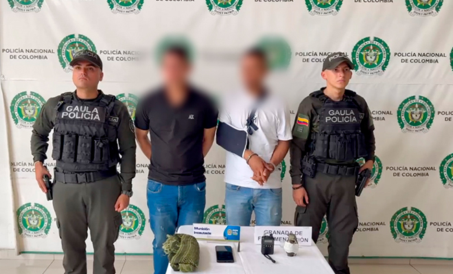 Dos personas capturadas con los elementos incautas siendo escoltados por dos funcionarios del grupo GAULA Santander