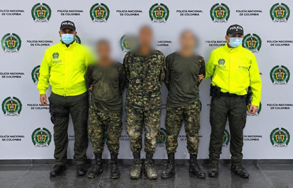 Dos polic&iacute;as custodiando tres personas capturadas