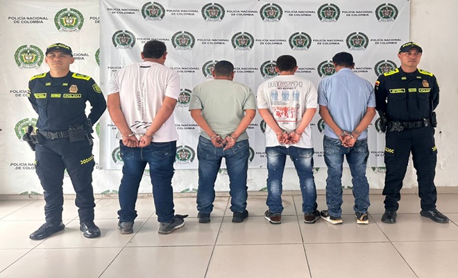 Dos policías custodiando cuatro capturados