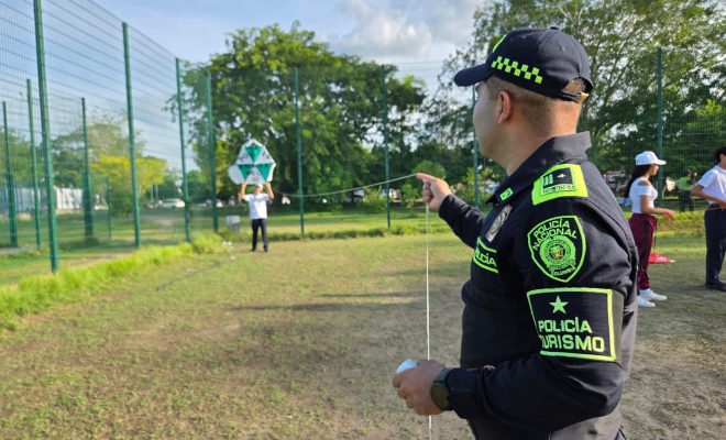 un Funcionario policial adscrito al grupo de turismo y patrimonio nacional volando una cometa en un parque