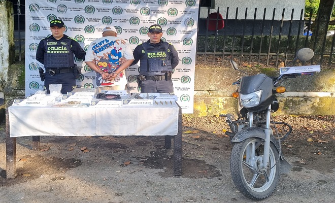 Policías custodian a capturado en la mesa se tienen los elementos incautados Droga, dinero motocicleta 