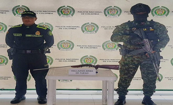 un funcionario policial y un funcionario del ejercito nacional con un arma de fuego en una mesa