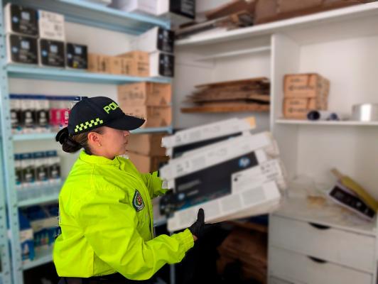 Funcionario de Policía Judicial, verificando los elementos de oficina hallados en los locales comerciales.