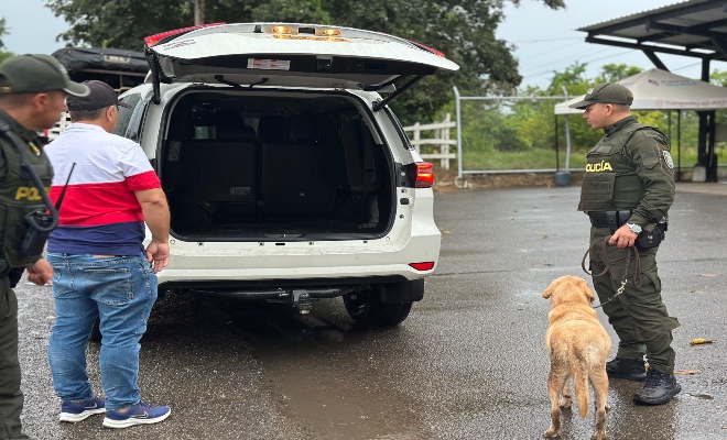 dos uniformados de la Policía nacional   y un canino realizando registro a vehículo en vía publica  