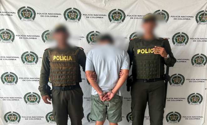 funcionarios policiales con un ciudadano capturado frente a pendón institucional