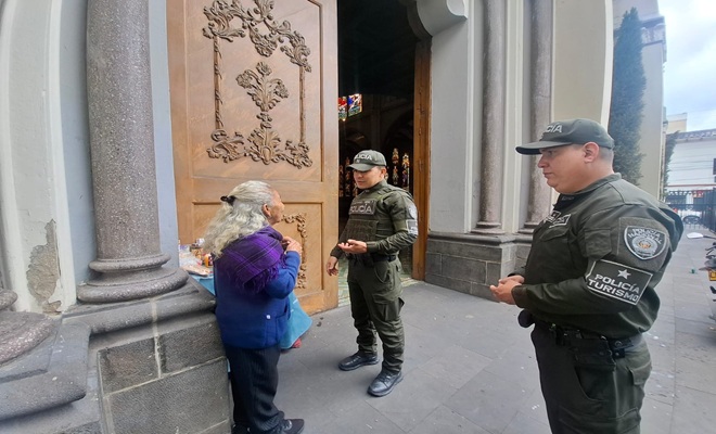 dos funcionarios policiales dando recomendaciones de seguridad a una ciudadana fuera del templo de Cristo Rey 