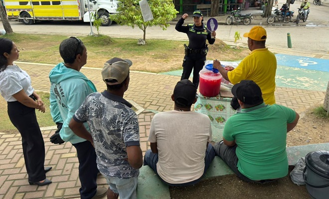 Una funcionaria policial dialogando con seis ciudadanos en v&iacute;a publica