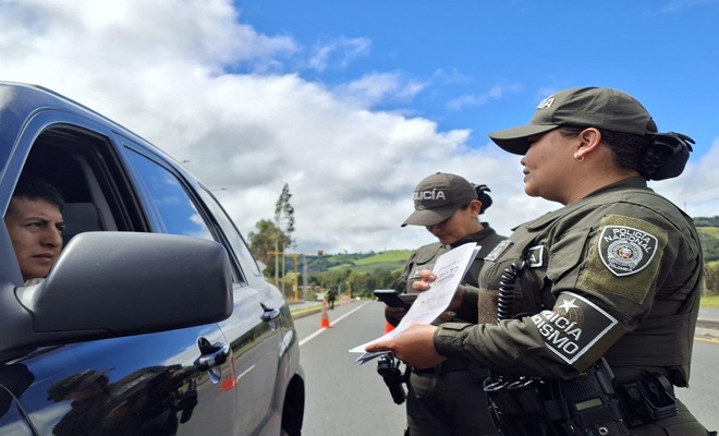 Dos funcionarios policiales frente a un autom&oacute;vil dando recomendaciones 