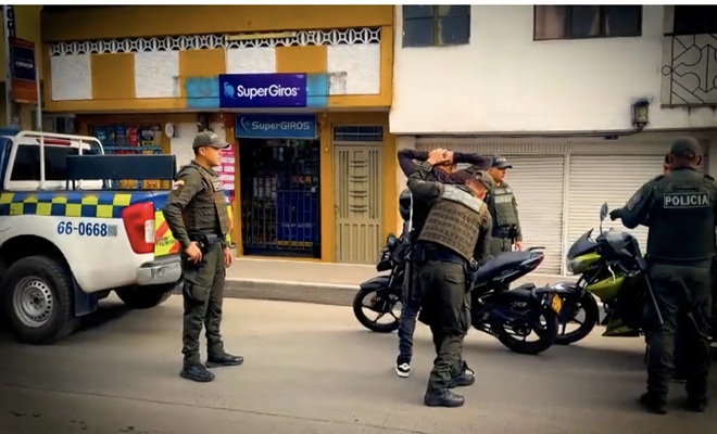 tres policiales de espaldas realizando un registro a personas en motocicleta 