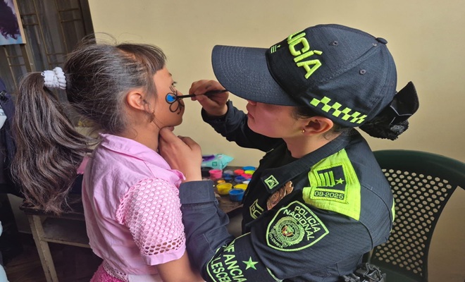 una funcionaria policial, pintando la carita a una ni&ntilde;a de espaldas 