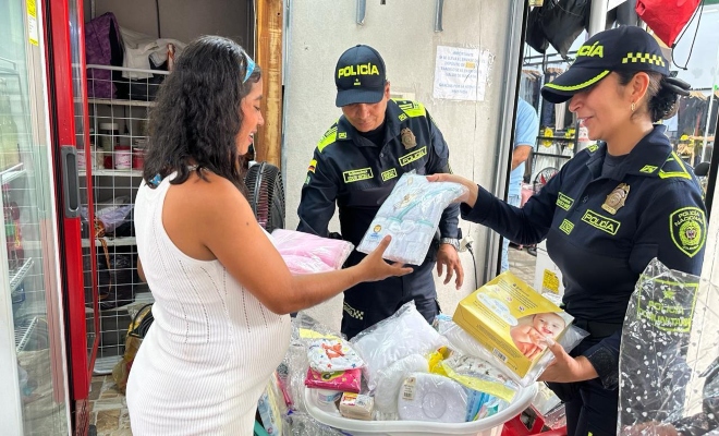 Dos uniformados realizando entrega de kit a una ciudadana embarazada 