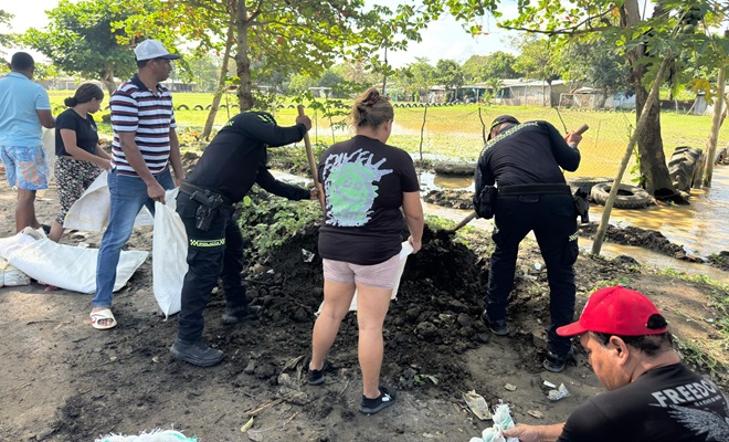 Polic&iacute;a y comunidad llenando costales con arena