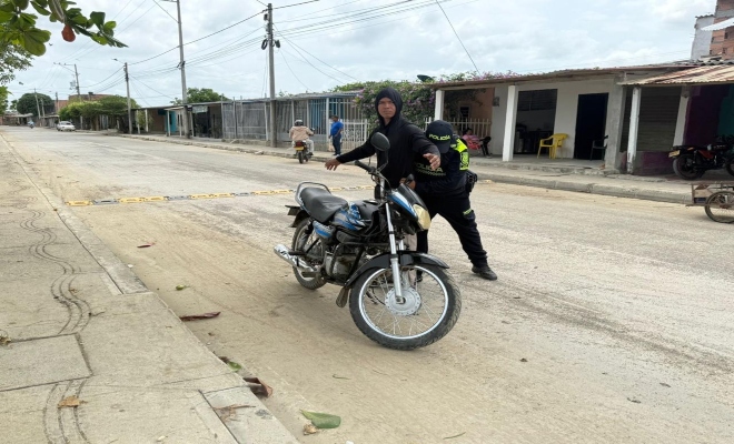 Un policia realizando registro a un ciudadano y una motocicleta 