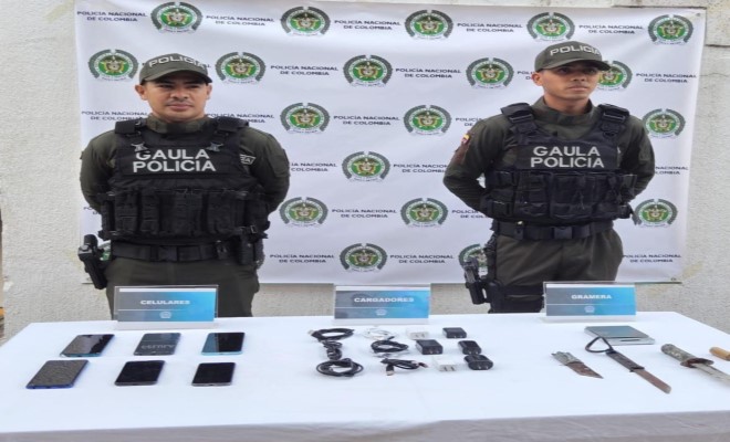 Dos funcionarios del grupo Gaula frente a elementos incautados tras el allanamiento de la carcel La Vega