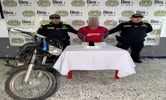 Dos policías con un capturado y una motocicleta
