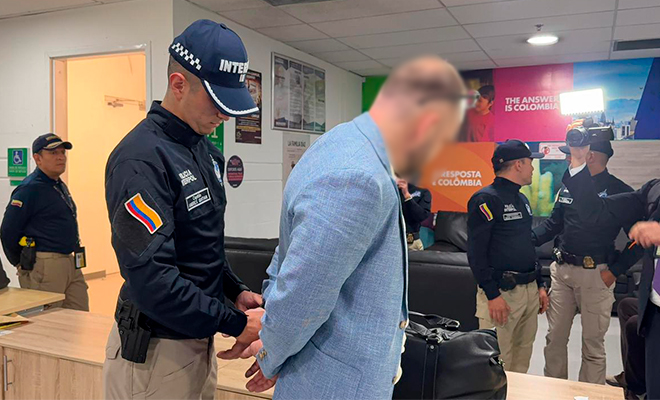 Funcionario de Interpol colocando esposas a persona retenida