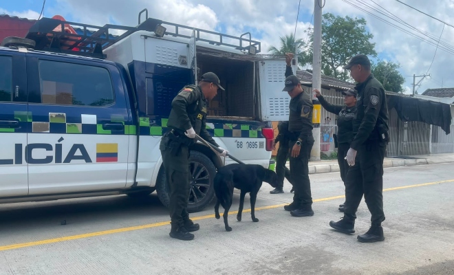 Cuatro funcionarios policiales frente a una camioneta institucional realizando el rescate de un perro 