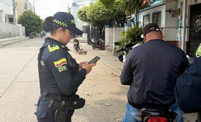 una uniformada realizando registro a veh&iacute;culo mediante dispositivo PDA 