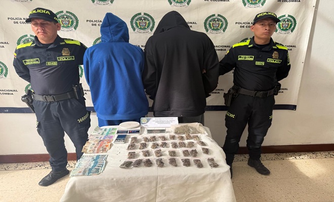Polic&iacute;as custodian personas capturadas, en la mesa se observan los elementos incautados