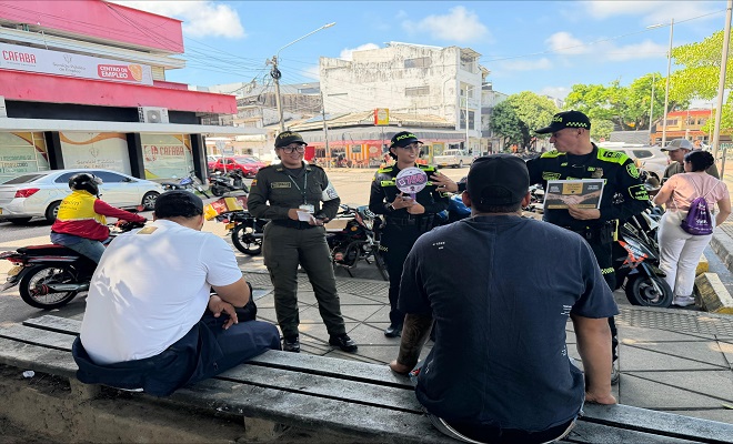 Tres funcionarios de la Policía Nacional realizando campaña de prevención al suicidio y socialización de las líneas de atención a dos ciudadanos en el parque Infantil de Barrancabermeja.