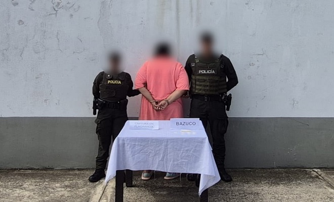 Policías toman de la mano a mujer que esta de espaldas, frente a ellos hay una meza con mantel 