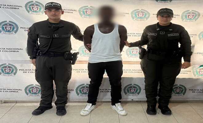 Un hombre capturado esposado con dos Polic&iacute;as en cada lado respectivamente 