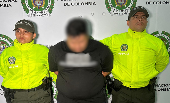 Un hombre se encuentra posiblemente detenido y custodiado por dos uniformados de la Policía Nacional.