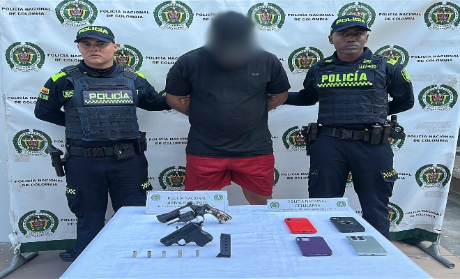 Dos polic&iacute;as, un capturado, encima de una mesa elementos incautados 