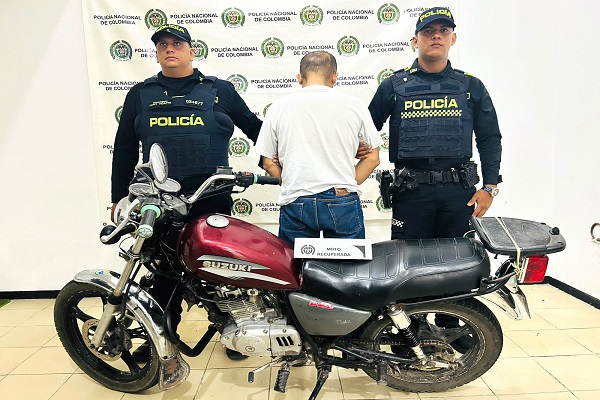 Dos Policías custodian a un capturado y motocicleta recuperada