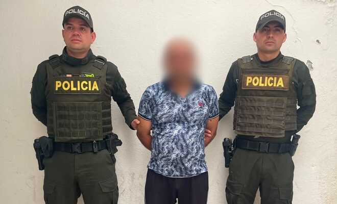 Un ciudadano capturado quien se encuentra esposado con dos policías en cada lado respectivamente 